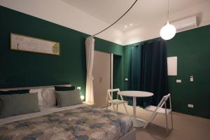 um quarto com paredes verdes, uma cama e uma mesa em Aquacharme em Palermo
