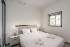 Un dormitorio blanco con una gran cama blanca y una ventana en New Branch Gindi Tower 1BR with Parking, en Tel Aviv