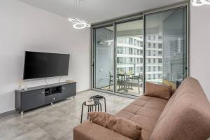 a living room with a couch and a flat screen tv at New Branch Gindi Tower 1BR with Parking in Tel Aviv