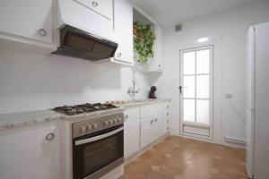 a white kitchen with a stove and a window at LC Apartaments Av del Mar in Castellón de la Plana