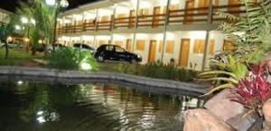 un coche aparcado frente a un edificio junto a un cuerpo de agua en Ville Park Hotel en Ourinhos