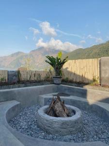 a stone fire pit in a yard with a fence at Ginastro Hom in Bangli