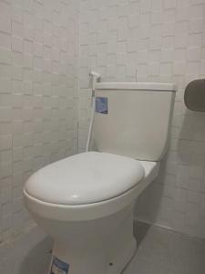 a white toilet in a bathroom with a wall at Ginastro Hom in Bangli