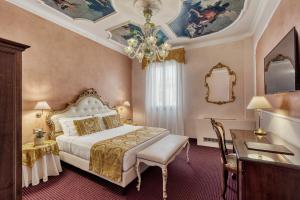 a bedroom with a bed and a desk and a chandelier at Hotel Pausania in Venice