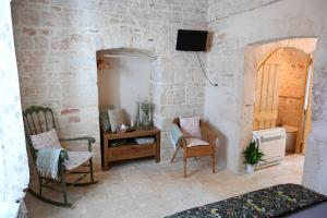 une chambre avec deux chaises, une table et une télévision dans l'établissement La Casetta, à Alberobello