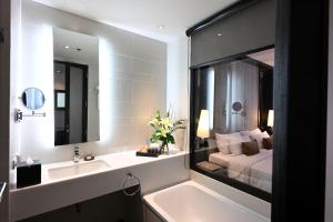a bathroom with a bed and a sink and a tub at Mövenpick Hotel Sukhumvit 15 Bangkok in Bangkok