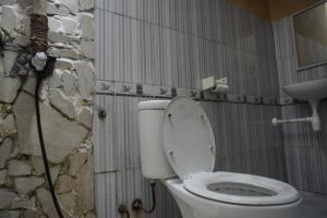 La salle de bains est pourvue de toilettes et d'un mur en pierre. dans l'établissement Kiayazo ViBES Inn, à Gili Trawangan