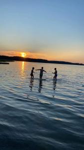 three people are standing in the water at sunset at Sterla - Masuria in Giżycko