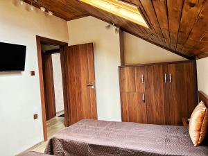 1 dormitorio con 1 cama, armarios de madera y TV en RELAX - Guest House Varshets, en Varshets