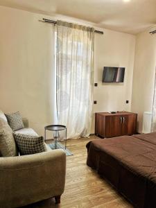 ein Schlafzimmer mit einem Bett, einem Sofa und einem TV in der Unterkunft RELAX - Guest House Varshets in Varshets