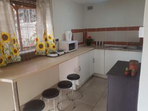 een keuken met 2 krukken en een aanrecht met een magnetron bij African Sky's the Limit - Budget, Quiet, Peaceful Self-Catering in Durban +30 foto's