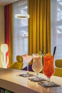 three cocktails sitting on top of a table at Golden Tulip Krakow City Center in Kraków