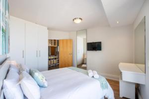 a bedroom with a white bed with a tv on the wall at Hibernian Towers 309 Strand - Luxury Self Catering in Cape Town +29 photos