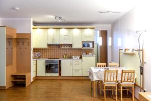 eine Küche mit weißen Schränken und einem Tisch mit Stühlen in der Unterkunft Atmoszféra Apartman in Sárvár