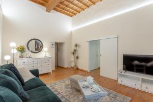 uma sala de estar com um sofá verde e uma televisão em La Perla Del Borgo Apartment em Florença