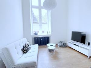 a white living room with a white couch and a tv at Loft Saint Thomas - Petite France in Strasbourg