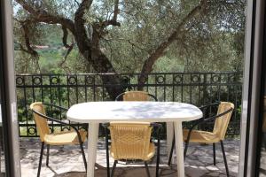 une table et des chaises blanches sur une terrasse avec un arbre dans l'établissement Villa Olive Tree with Private Pool, à Luštica