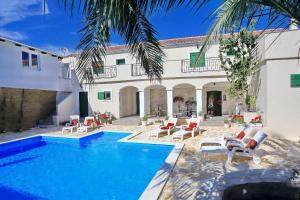 a swimming pool with chairs and a house at Didovi dvori in Bibinje