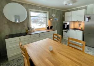 una cucina con tavolo in legno e grande specchio di Cozy house in an Arctic village 