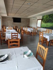 uma sala de jantar com mesas brancas e cadeiras de madeira em El retiro hotel rural em Moratalla