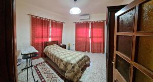um quarto com uma cama e cortinas vermelhas em Feel home always em Amã