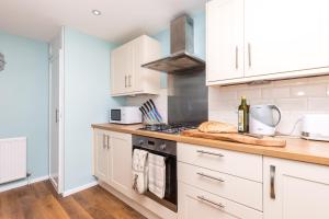 a kitchen with white cabinets and a stove top oven at Rivermead in Horsham