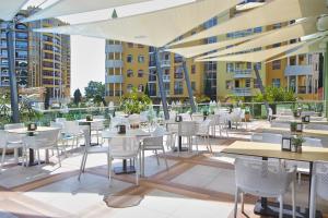 ein Restaurant mit weißen Tischen und Stühlen und Gebäuden in der Unterkunft Hotel MARVEL - FULLY RENOVATED FREE Beach Access in Sonnenstrand