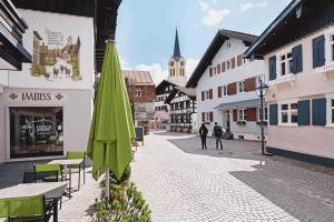 a street with tables and a green umbrella and buildings at Le Bouveret - Ferienwohnungen Reinartz in Oberstaufen
