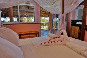 een slaapkamer met een wit bed met rode decoraties erop bij VILLA PANORAMA NOSY BE in Nosy Be