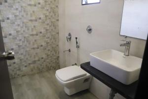 a bathroom with a white toilet and a sink at Hotel Grand Ambience in Gandhidham