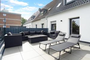 a patio with a couch and chairs on a roof at Appartment Weiden in Gronau