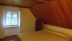 Schlafzimmer mit einem Bett mit Holzdecke und einem Fenster in der Unterkunft LA CASA DEI RICORDI in Lanna