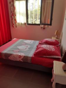 een slaapkamer met een bed met rode en grijze lakens en ramen bij chez laly et mimy in La Possession