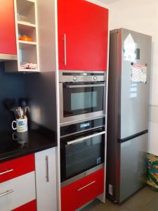 een keuken met een roestvrijstalen koelkast en rode kasten bij chez laly et mimy in La Possession