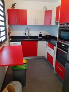 een keuken met rode en witte kasten en een wastafel bij chez laly et mimy in La Possession