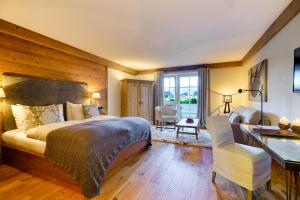 a bedroom with a large bed and a desk at Posthotel Achenkirch Resort and Spa - Adults Only in Achenkirch