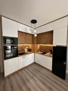 a kitchen with white cabinets and a black refrigerator at SkyTravel 27 Apartament Pileckiego Nowy Dwór Mazowiecki Airport Modlin 24H in Nowy Dwór Mazowiecki