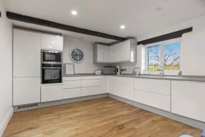 a kitchen with white cabinets and a wooden floor at Foxen Holes Cottage in Saundersfoot