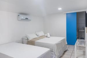 um quarto branco com 2 camas e uma parede azul em Pousada La Bella Luna em Porto de Galinhas