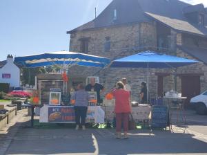 a group of people standing in front of a market with umbrellas at Chambre chez l'habitante "Bambou" in Derval