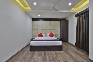 Un dormitorio con una cama con almohadas rojas. en Hotel Grand Ambience en Gandhidham