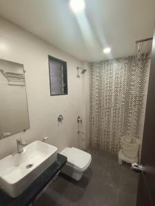 ein Bad mit einem Waschbecken, einem WC und einer Dusche in der Unterkunft Hotel Grand Ambience in Gandhidham