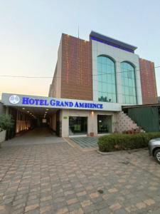 Una gran entrada del hotel con un coche aparcado delante en Hotel Grand Ambience, en Gandhidham