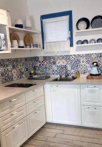 a kitchen with white cabinets and blue and white tiles at Suite paradise - E013 garden apartment in Caesarea