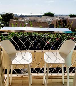 dos copas de vino sentadas en una mesa en un balcón en Suite Paradise - D111, en Cesarea