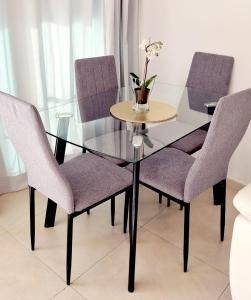 una mesa de cristal con sillas moradas y un jarrón con flores en Suite Paradise - D111 en Caesarea