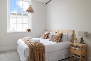 a white bedroom with a large white bed with pillows at Apartment 5 Y Capel, Zip-link beds, Free on site parking, very close to town centre amenities and A55 expressway in St Asaph