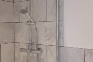 a shower with a shower head in a bathroom at Apartment 5 Y Capel, Zip-link beds, Free on site parking, very close to town centre amenities and A55 expressway in St Asaph
