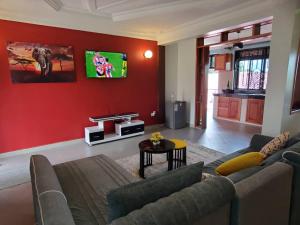 uma sala de estar com um sofá e uma parede vermelha em cosy living em Gulu