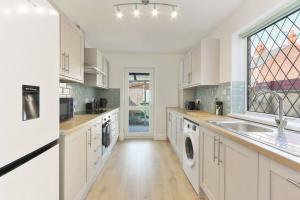 cocina con armarios blancos, fregadero y ventana en Modern home near Alexandra Dock, en Great Coates